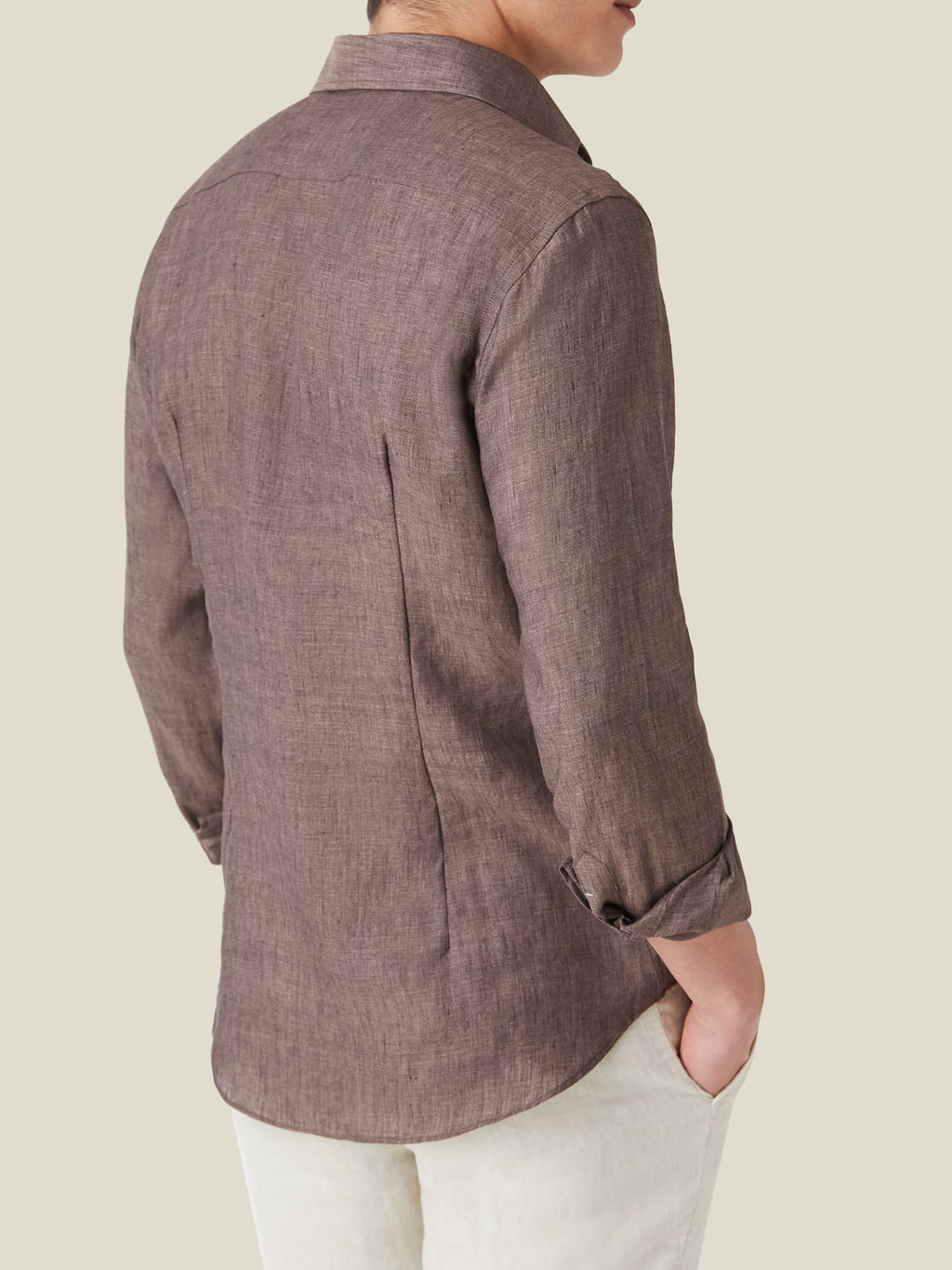 Back view of a model wearing the Chocolate Brown Portofino Linen Shirt, showing back darts and rolled sleeves.