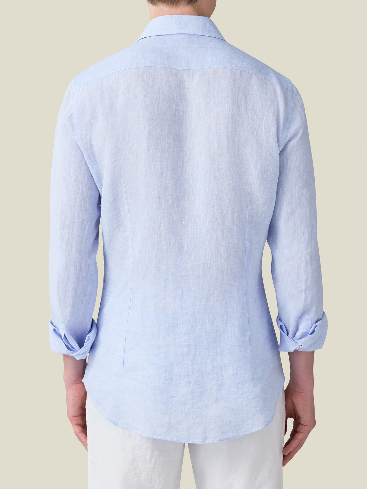 Back view of a model wearing the Portofino Linen Shirt in sky blue with the sleeves rolled up.