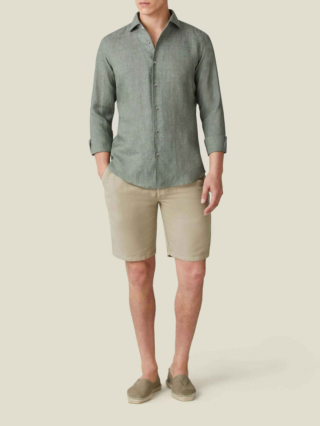 Front view of a model wearing the Portofino Linen Shirt in Safari Green, styled with beige shorts and espadrilles.