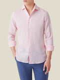 Model wearing the Luca Faloni light pink Portofino linen shirt with rolled-up sleeves and blue trousers.