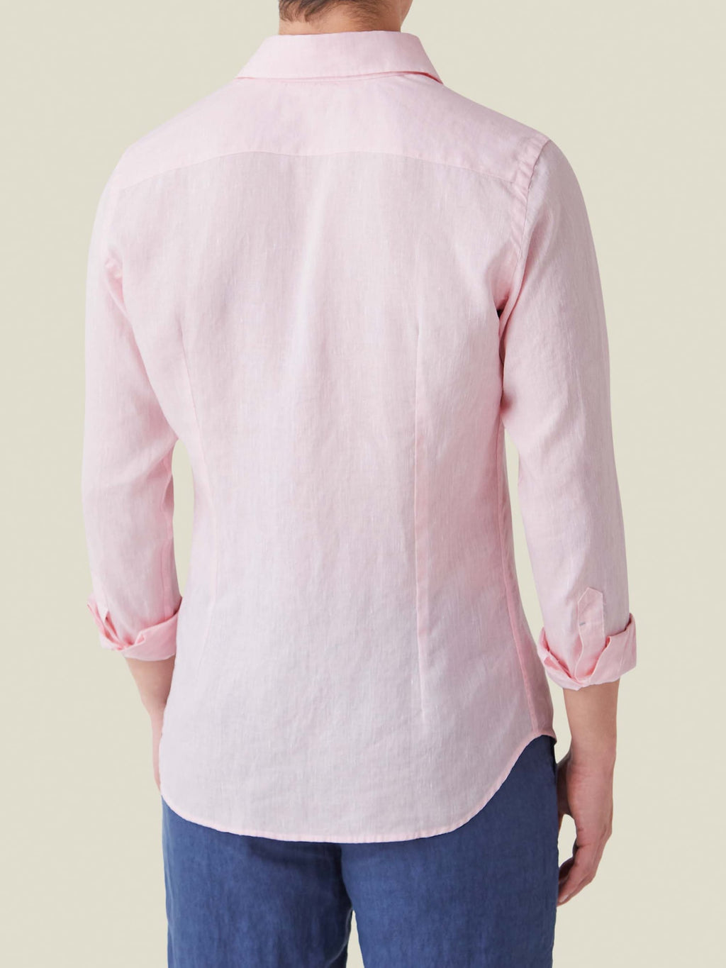 Back view of a man wearing the light pink Portofino Linen Shirt, showcasing its tailored fit and rolled-up sleeves.