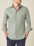 A model wears the Portofino Linen Shirt in sage green with the sleeves rolled up, shown from the front.