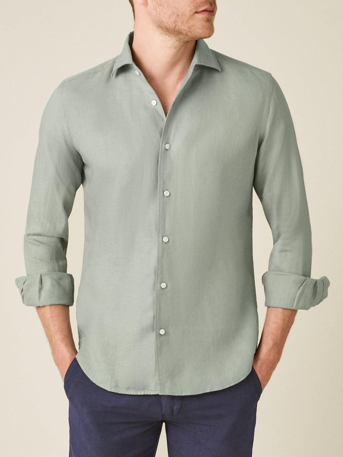 A model wears the Portofino Linen Shirt in sage green with the sleeves rolled up, shown from the front.