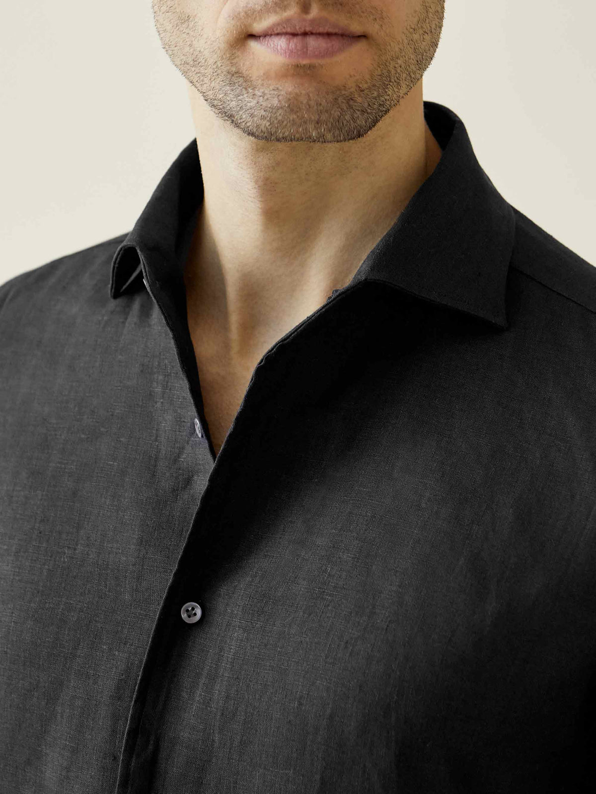 Close-up of a model wearing the black Portofino Linen Shirt, showcasing its signature one-piece Paramontura collar.