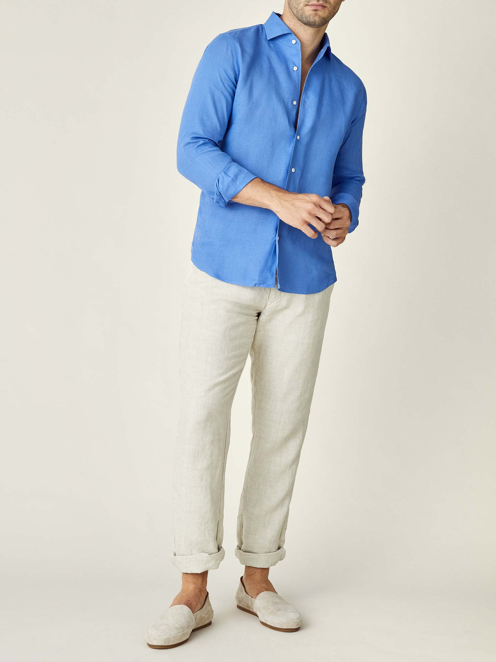A full-length view of a model wearing the Portofino Linen Shirt in Capri Blue with off-white trousers and loafers.
