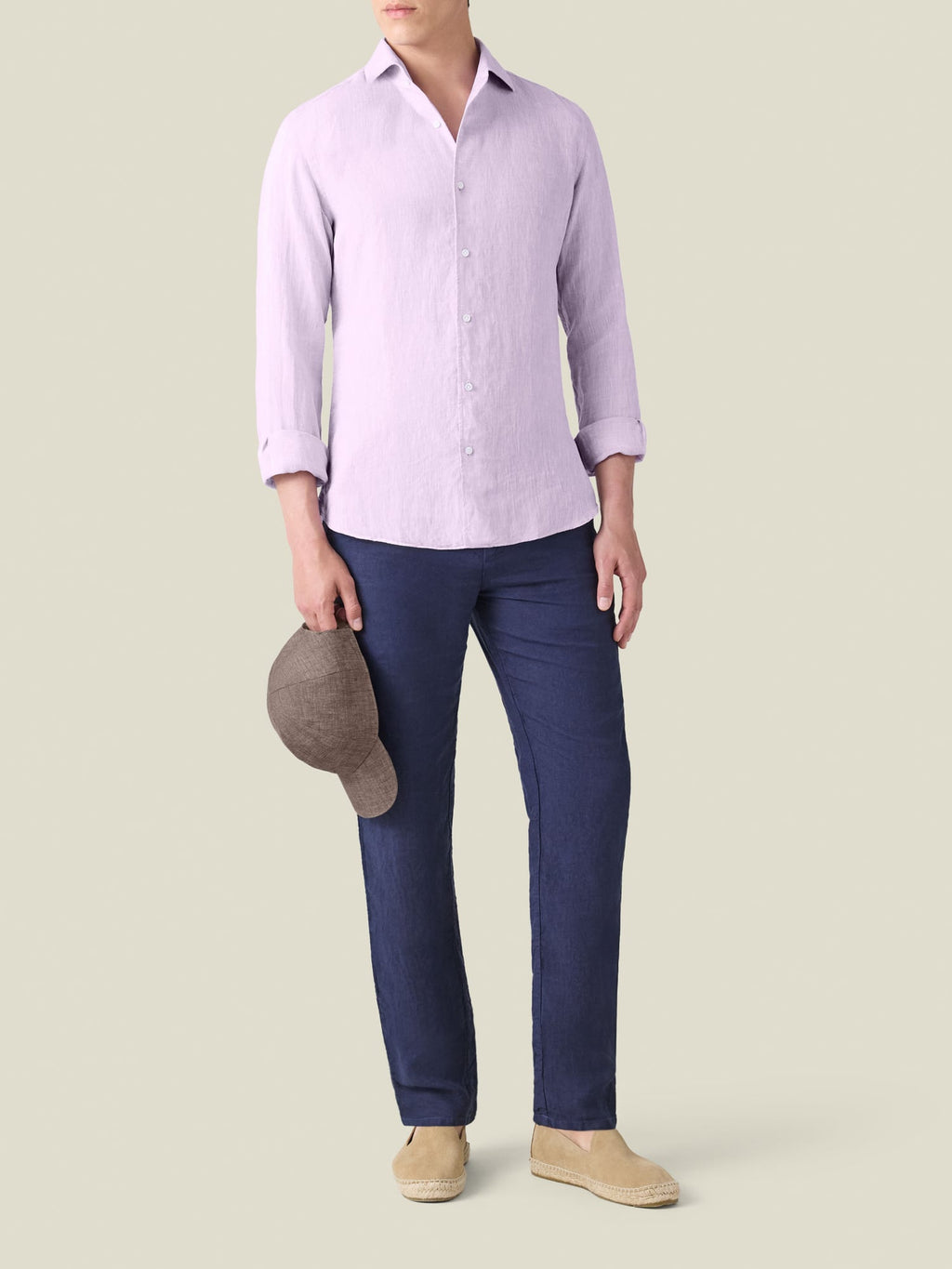 Man wearing the Portofino Linen Shirt in lilac, styled with navy trousers and beige espadrilles.