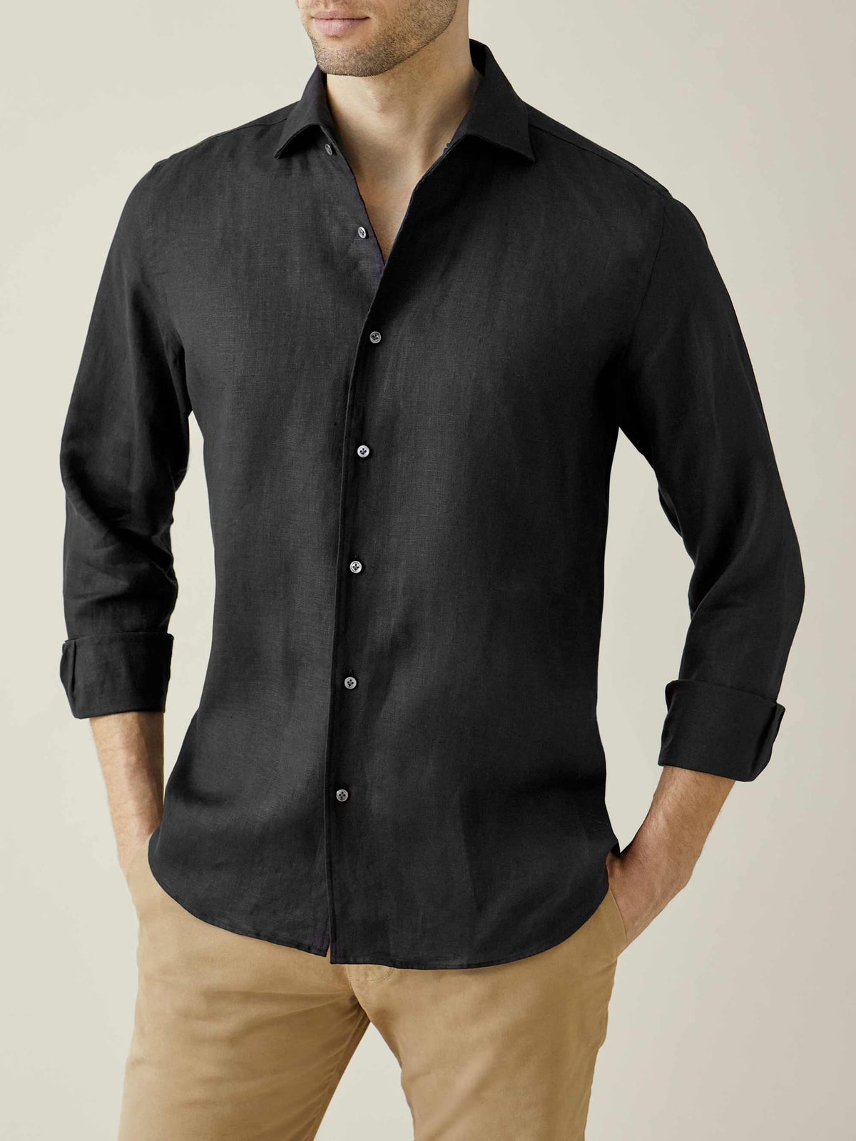 Front view of a model wearing the Luca Faloni Portofino Linen Shirt in black, styled with rolled sleeves and tan chinos.