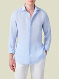 Front view of a model wearing the Portofino Linen Shirt in Sky Blue, with sleeves rolled up and styled with white trousers.