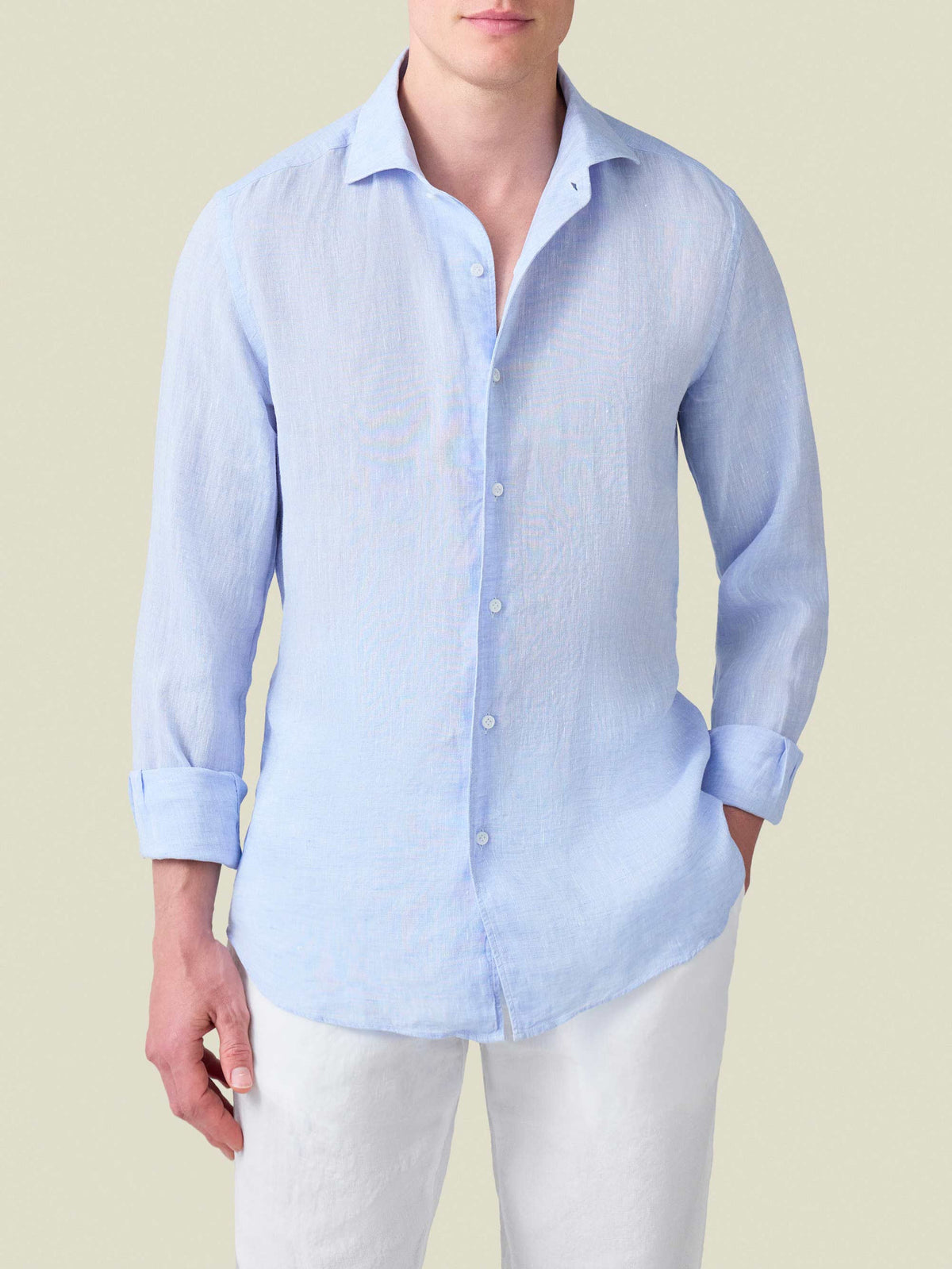 Front view of a model wearing the Portofino Linen Shirt in Sky Blue, with sleeves rolled up and styled with white trousers.