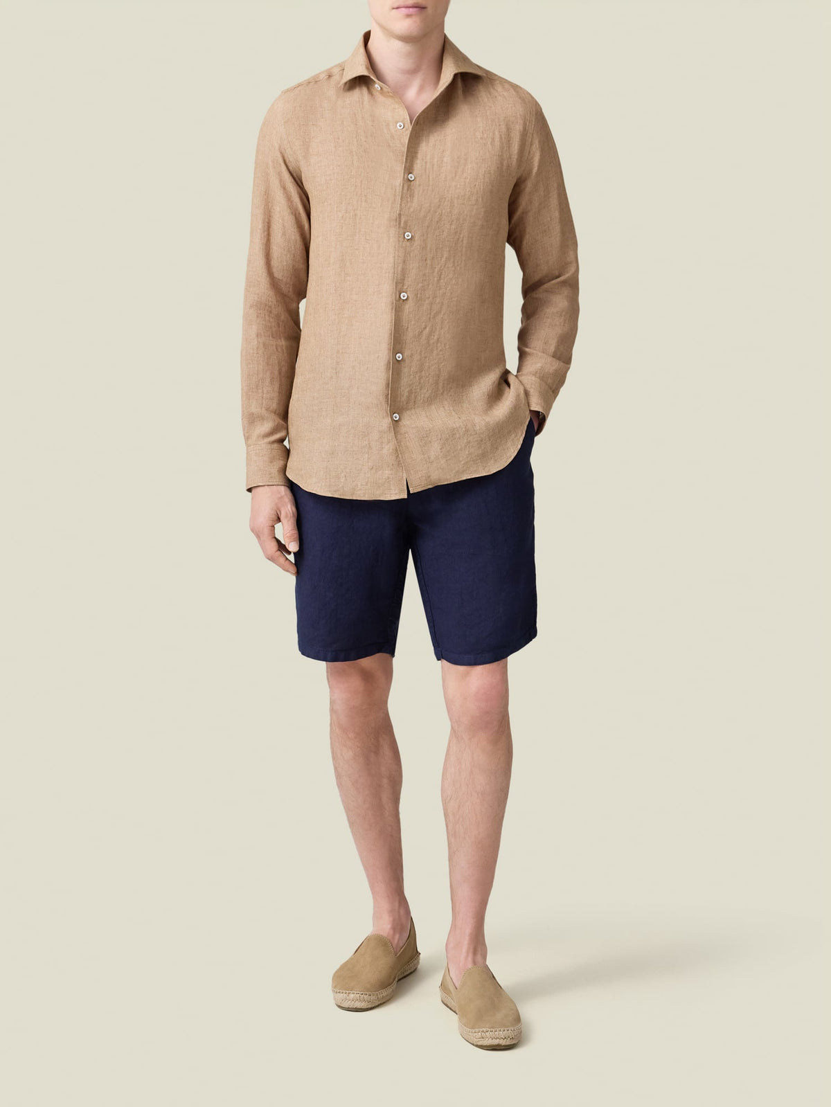 Full-length shot of a model wearing the Portofino Linen Shirt in Caramel Brown with navy shorts and tan espadrilles.