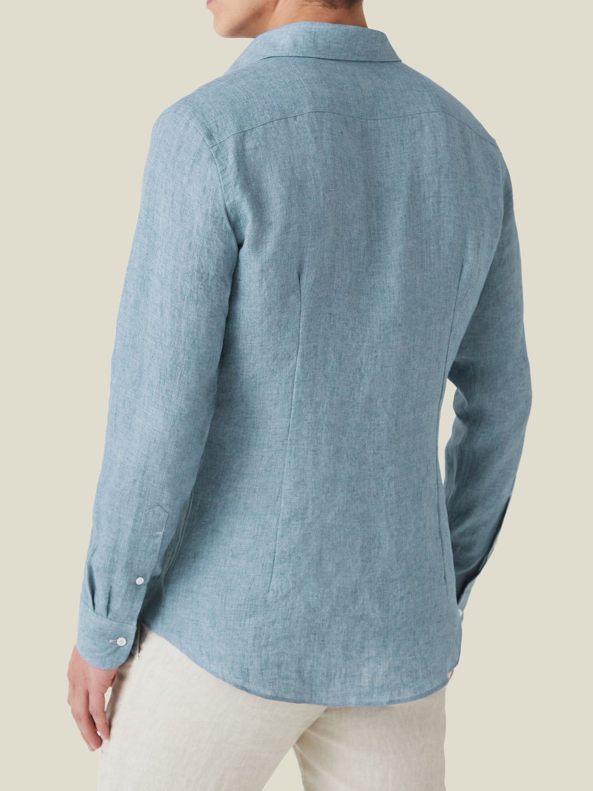 Back view of a man wearing the Portofino Linen Shirt in French Blue, showcasing its tailored fit and curved hem.