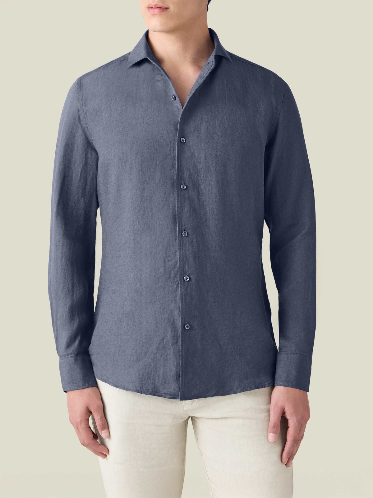 Front view of a man wearing the Luca Faloni Portofino Linen Shirt in Payne's Grey, paired with light-coloured trousers.