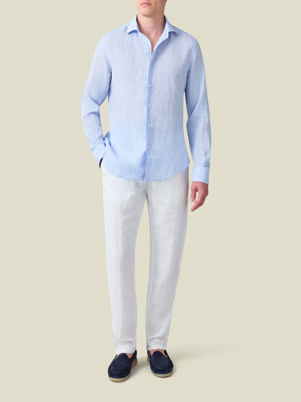 Full-length shot of a model wearing the sky blue Portofino Linen Shirt with white trousers and navy loafers.