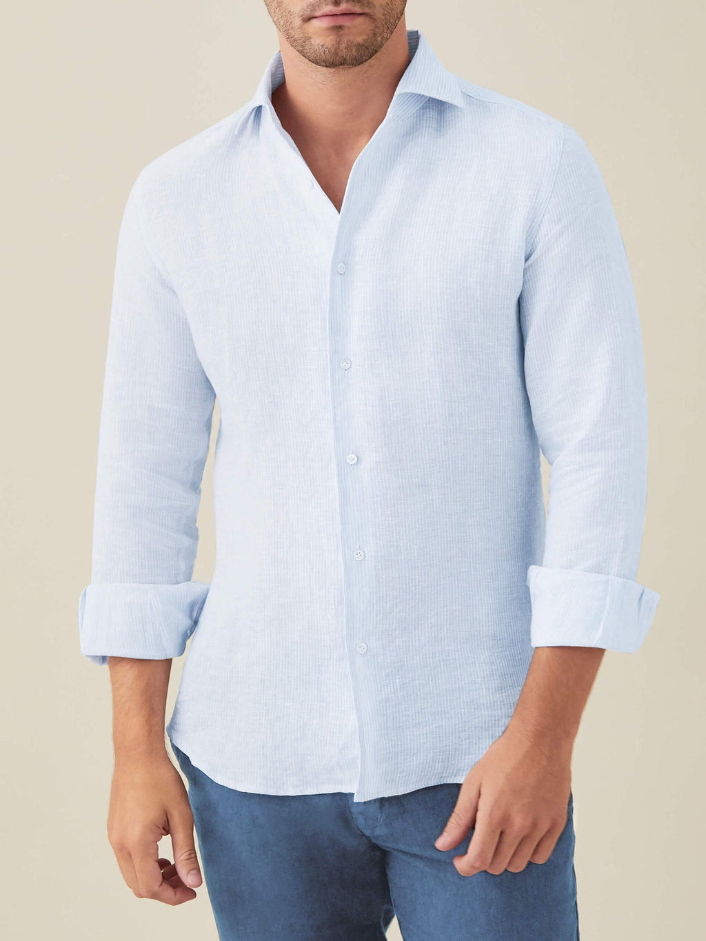 A front view of a model wearing the Luca Faloni Portofino Linen Shirt in Striped Sky Blue with the sleeves rolled up.