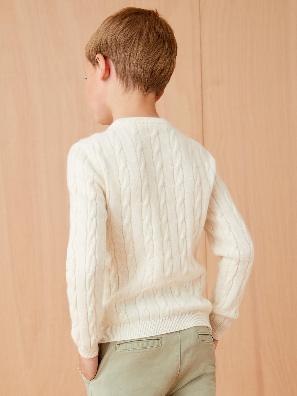 Back view of a model wearing the Ivory Junior Cable Knit, showcasing the cable knit texture pattern.