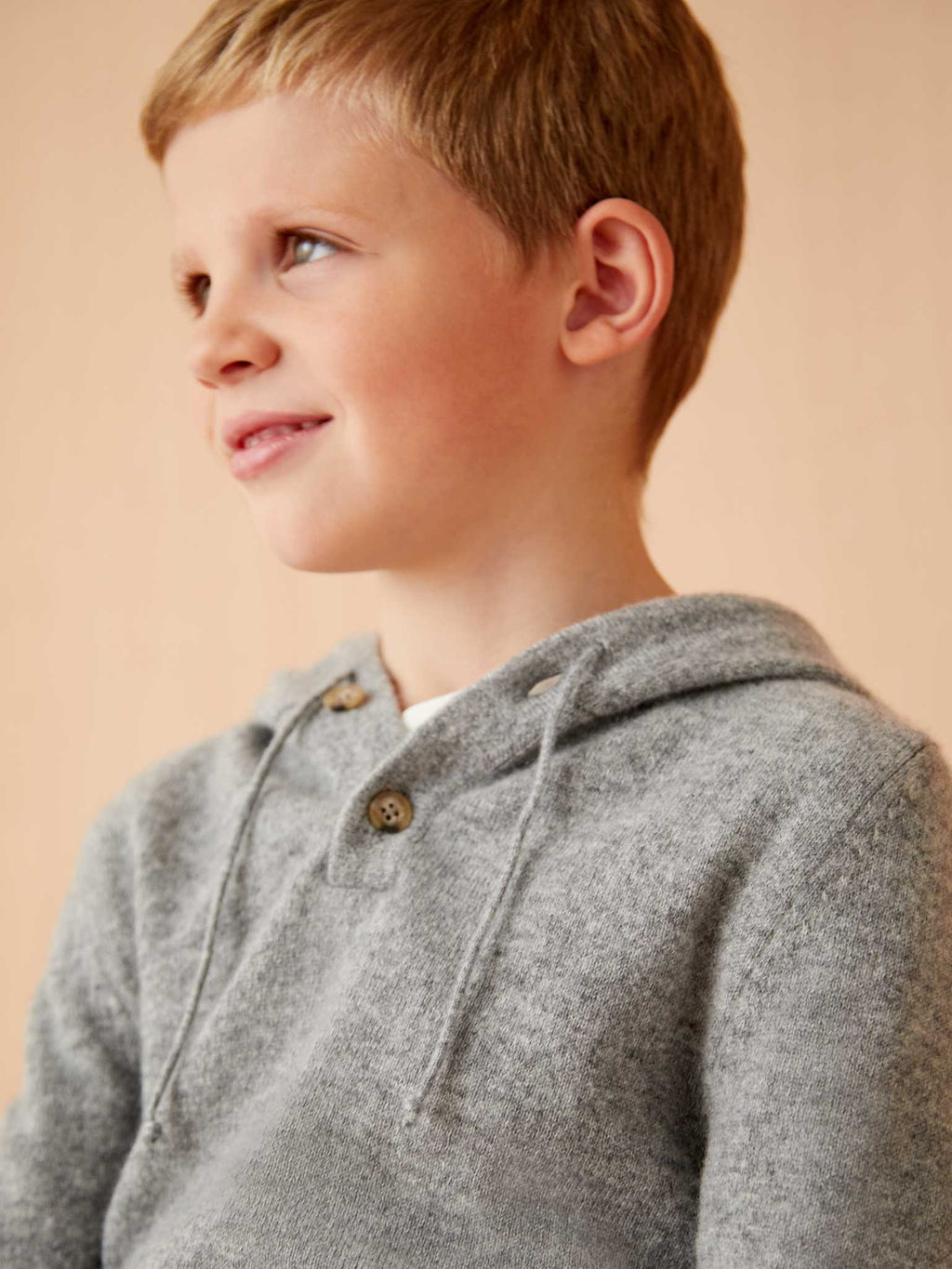 A young boy wearing the soft Dolomiti Grey Junior Cashmere Hoodie, showing the buttoned placket and hood detail.