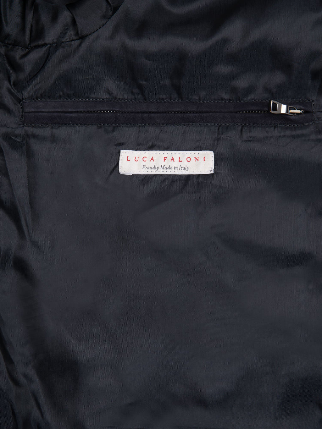 Close-up of the interior of the navy blue Classic Bomber Jacket, showing the premium lining, zipped pocket, and label.