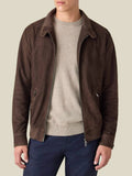 A model wears the Classic Bomber Jacket in chocolate brown goatskin suede, open over a beige sweater and dark jeans.