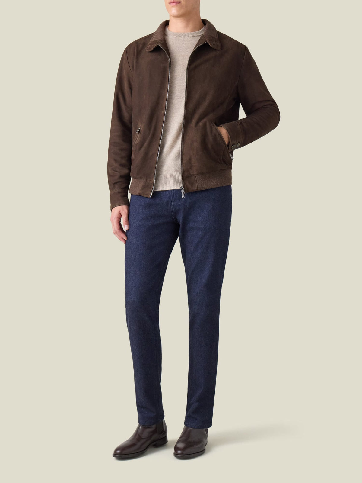 A front view of a model wearing the Classic Bomber Jacket in chocolate brown suede with dark jeans and brown boots.