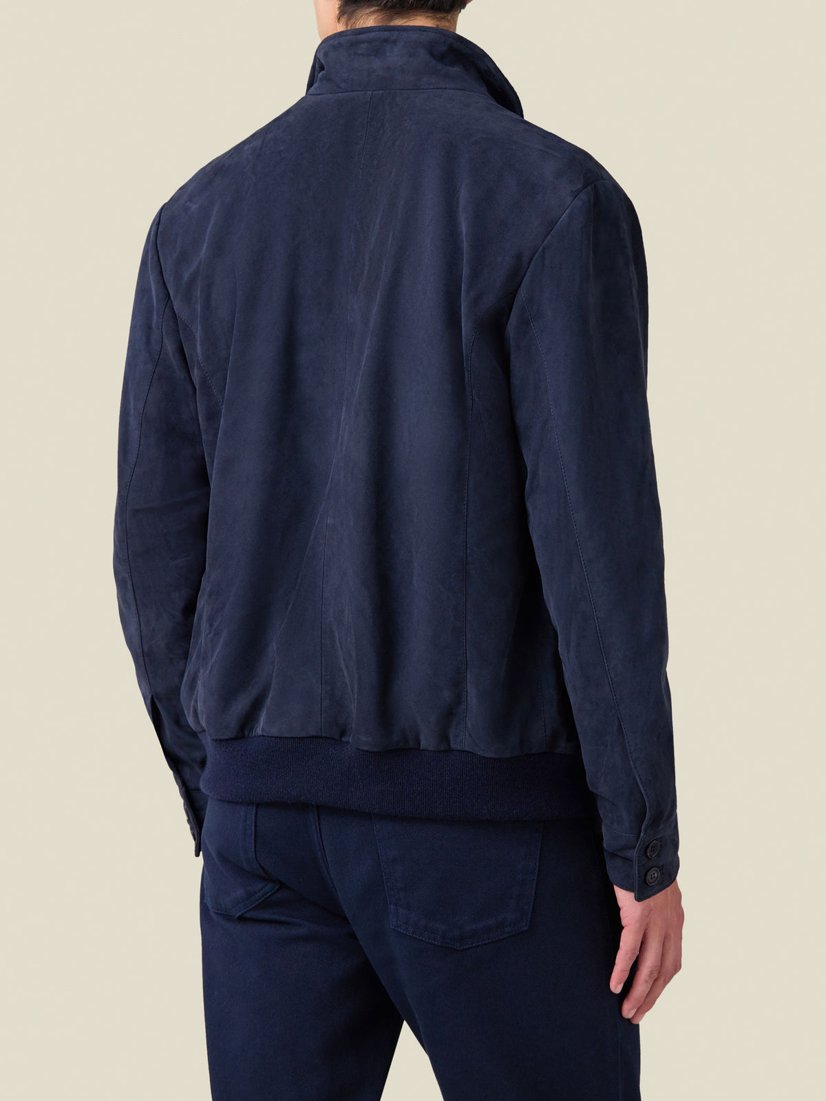 Back view of a man wearing the Classic Bomber Jacket in navy blue goatskin suede, showing the smart-casual silhouette.