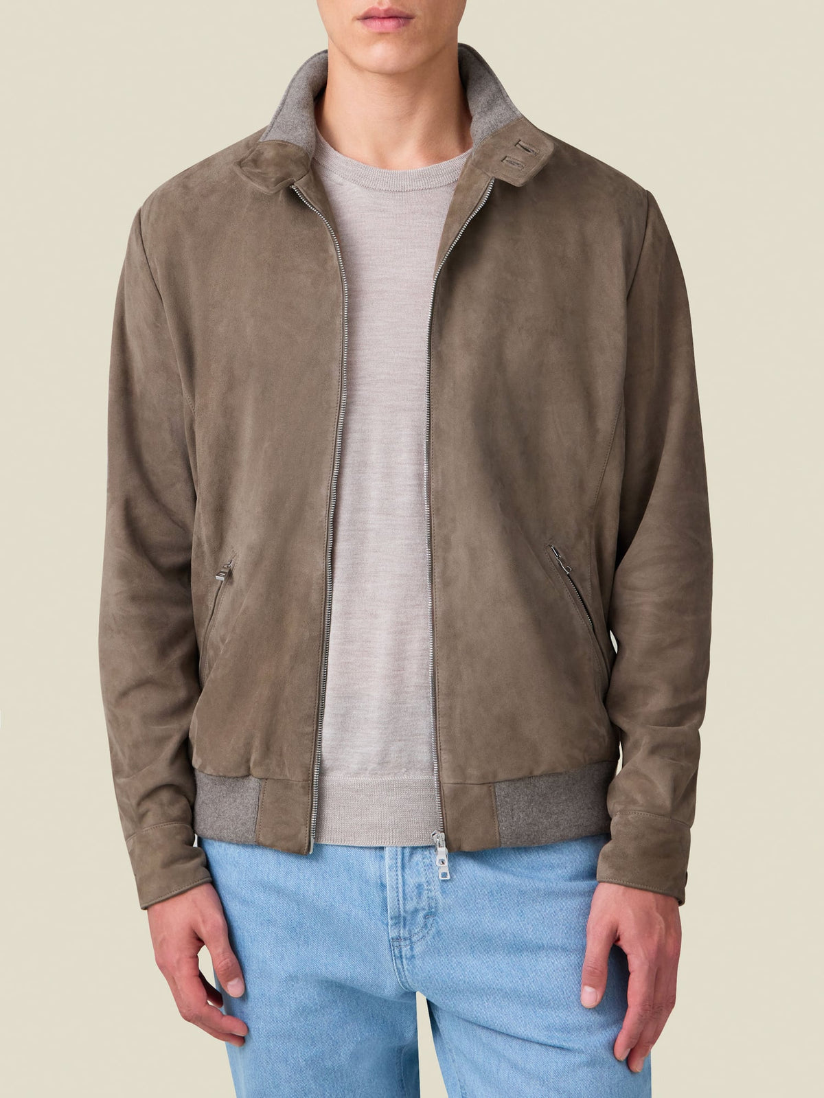 A model wears the Luca Faloni Classic Bomber Jacket in Hazelnut Brown suede, styled with a grey knit and light wash jeans.