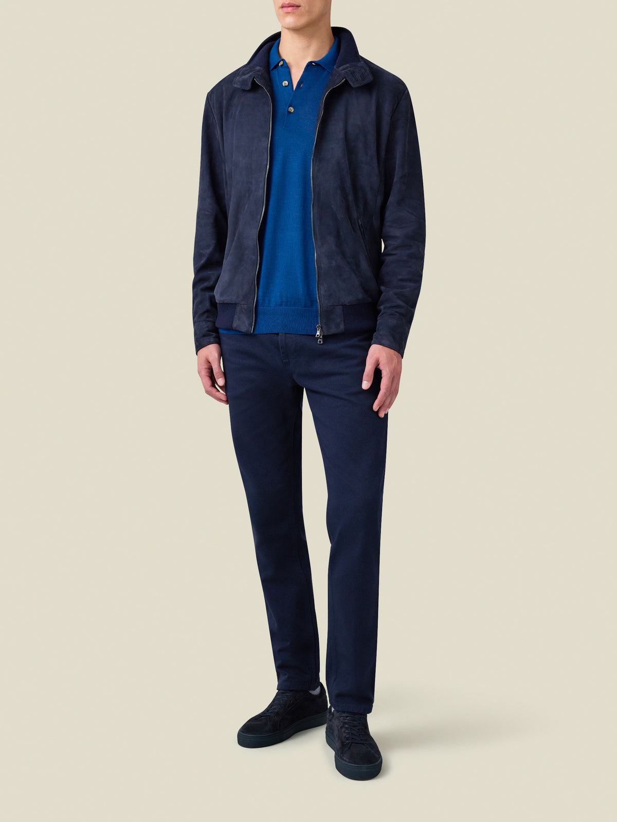 Full view of a model wearing the Classic Bomber Jacket in navy blue suede, styled open over a polo and trousers.