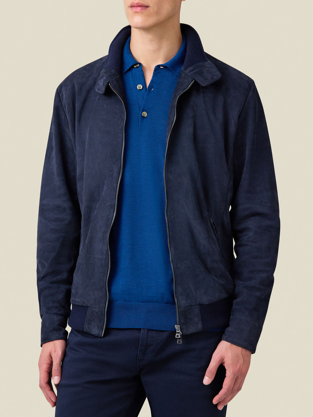 A front view of a model wearing the Navy Blue Classic Bomber Jacket in goatskin suede, styled open over a blue polo shirt.