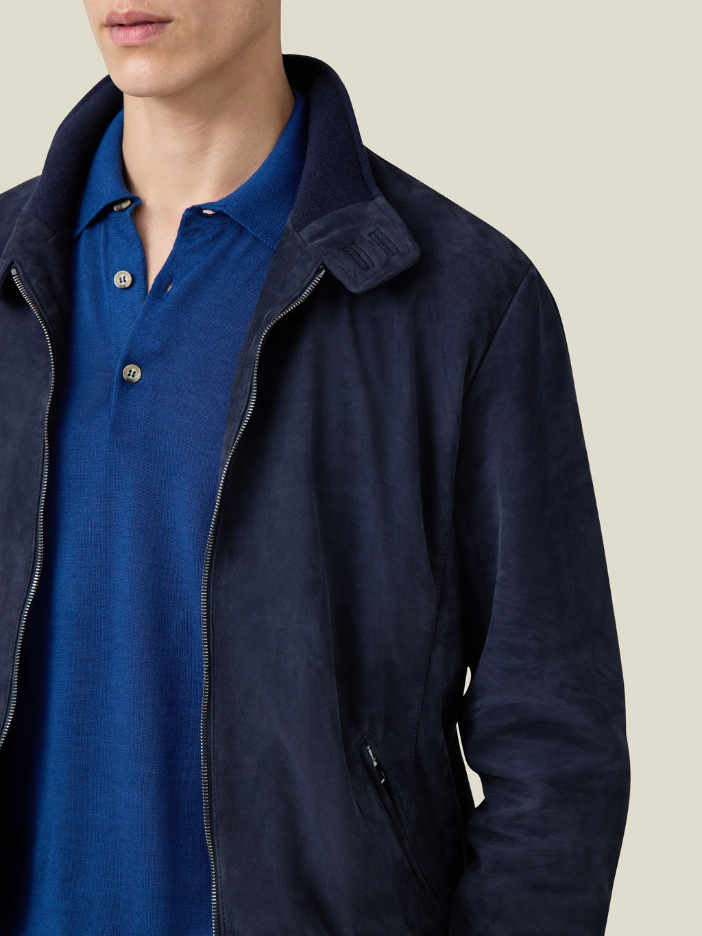 A close-up of a man wearing the navy blue suede Classic Bomber Jacket, highlighting the collar, zip, and fabric texture.