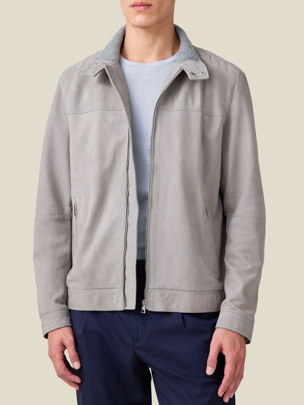 Front view of a model wearing the light grey suede Classic Racer Jacket open over a light blue t-shirt and dark trousers.