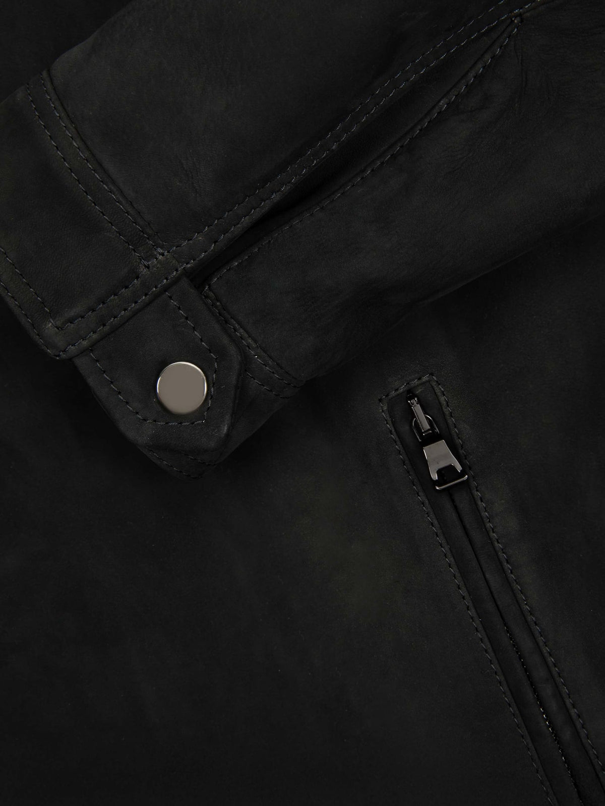 A close-up of the black Classic Racer Jacket in goatskin suede, detailing the press-stud cuff and a zipped pocket.