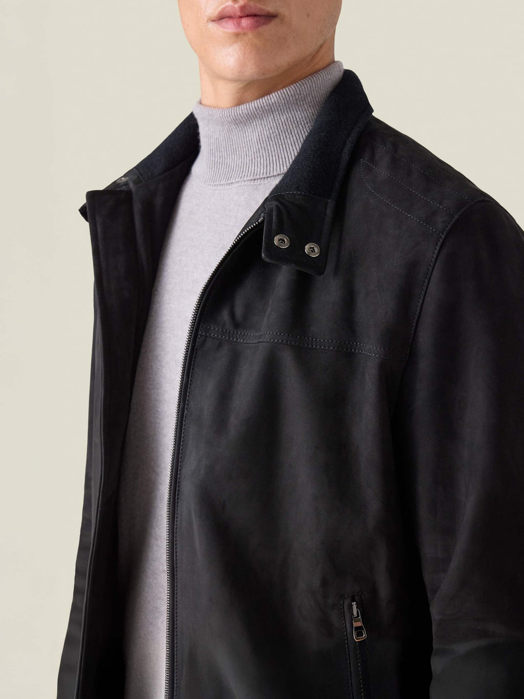 A model wears the black Classic Racer Jacket, with a close-up on the goatskin suede, zip front, and press-stud collar.