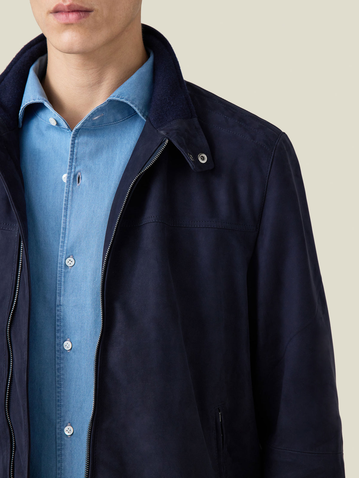 Detailed shot of a model wearing the navy suede Classic Racer Jacket over a blue shirt, focusing on the collar and zip.