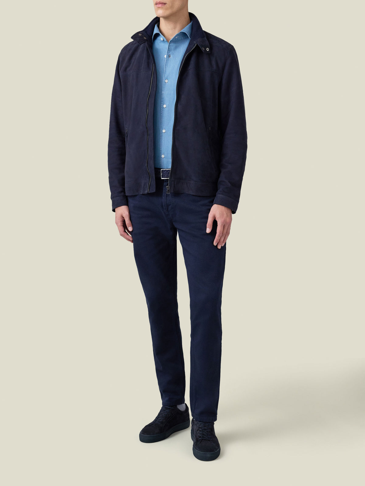 Full length shot of a model wearing the navy suede Classic Racer Jacket, with a light blue shirt and navy trousers.