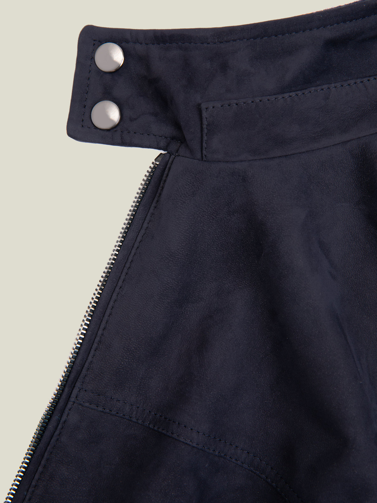 Close-up of the navy blue suede Classic Racer Jacket, highlighting the upright collar with double press-studded buttons.