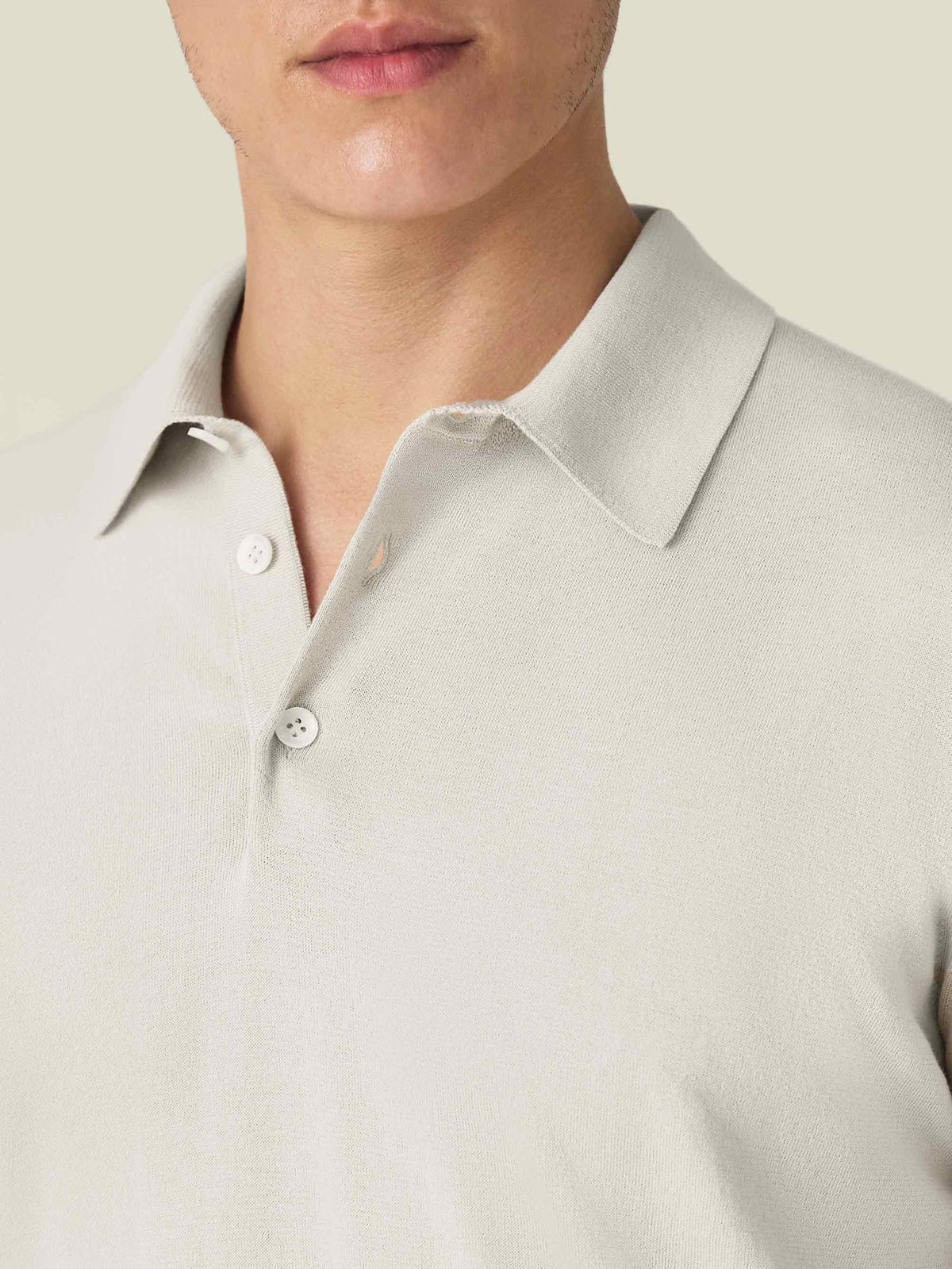 A close-up of the Knitted Cotton Polo in Sand, detailing the soft knit texture, collar, and mother-of-pearl buttons.