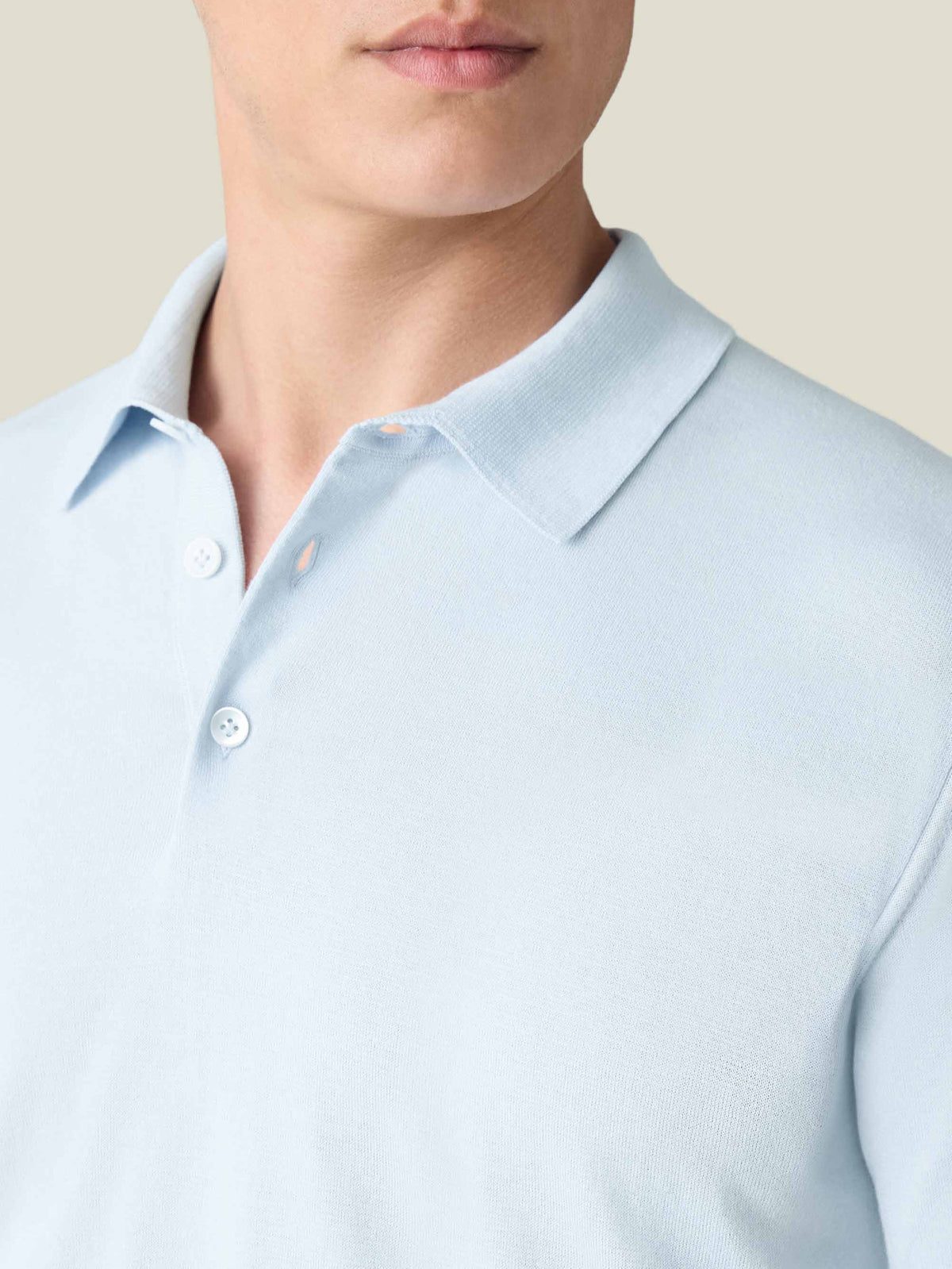 Close-up of a model wearing the light blue Knitted Cotton Polo, showing the knit texture, collar, and button placket.