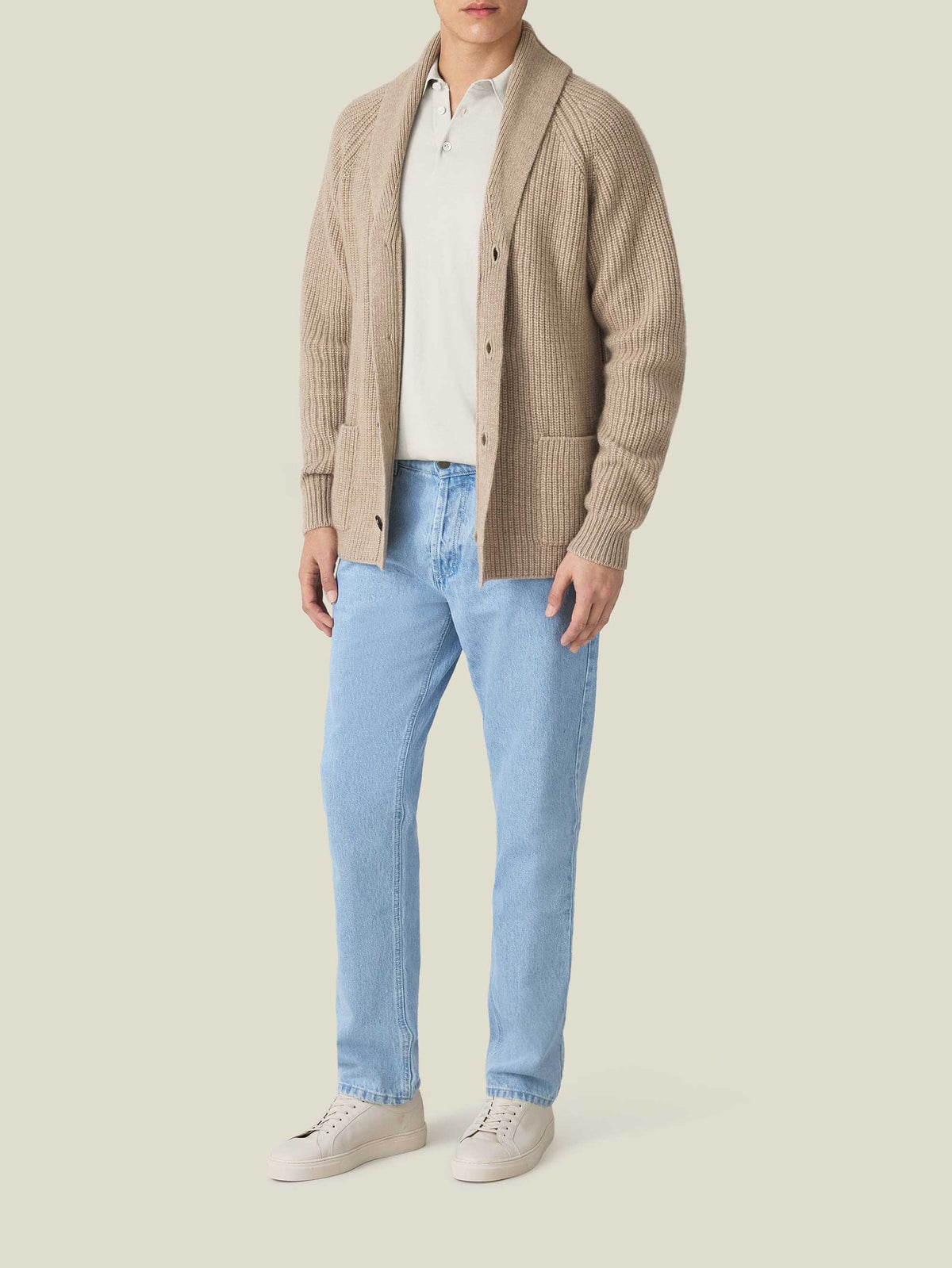Model styled in the Sand Knitted Cotton Polo, layered under a cardigan and paired with light wash jeans and sneakers.