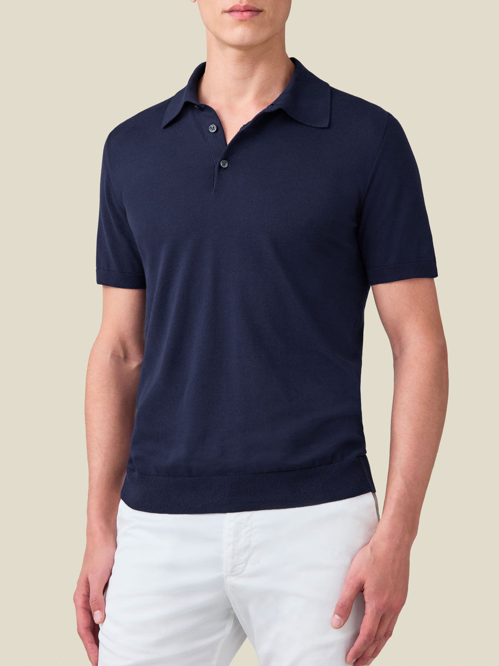 Front view of a man wearing the Luca Faloni Knitted Cotton Polo in Midnight Blue, styled with white trousers.