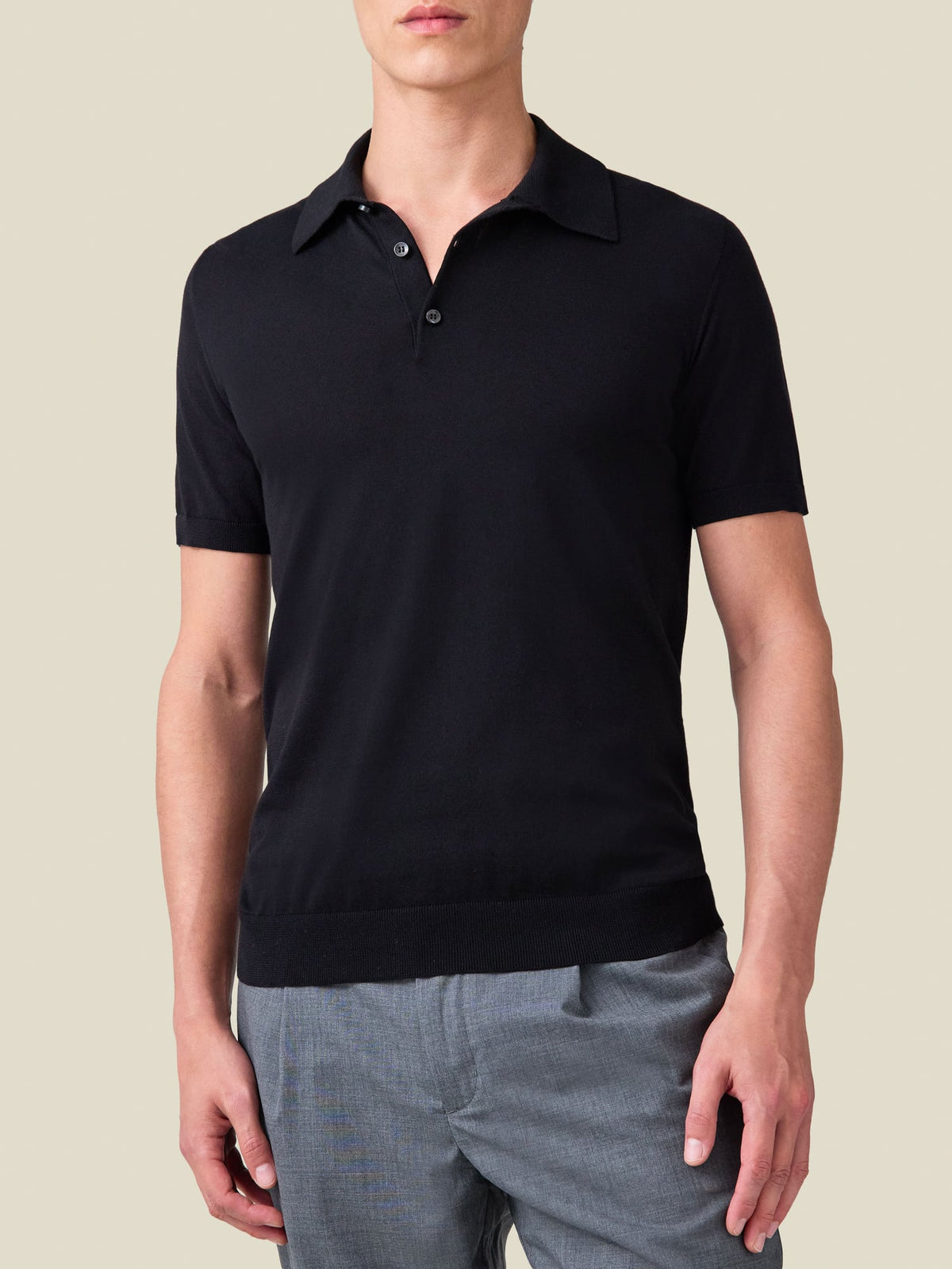 Front view of a model wearing the Luca Faloni black Knitted Cotton Polo with grey trousers.