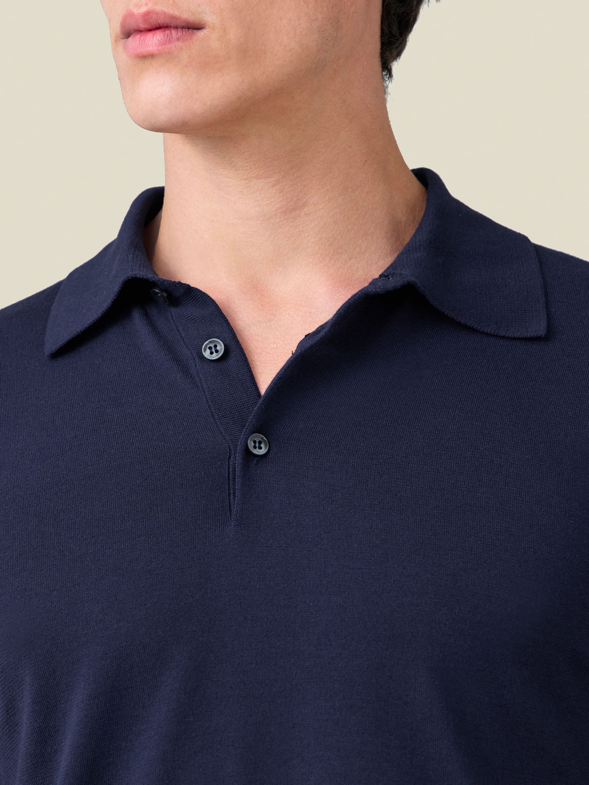A close-up of a man wearing the Midnight Blue Knitted Cotton Polo, highlighting the collar and mother of pearl buttons.