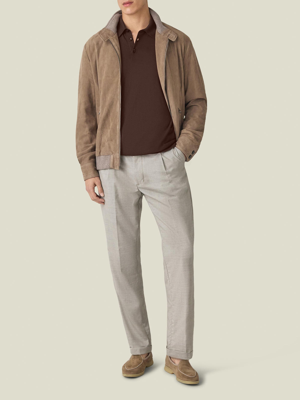 Man wearing the Chocolate Brown Knitted Cotton Polo, styled with a light brown suede jacket and light-coloured trousers.