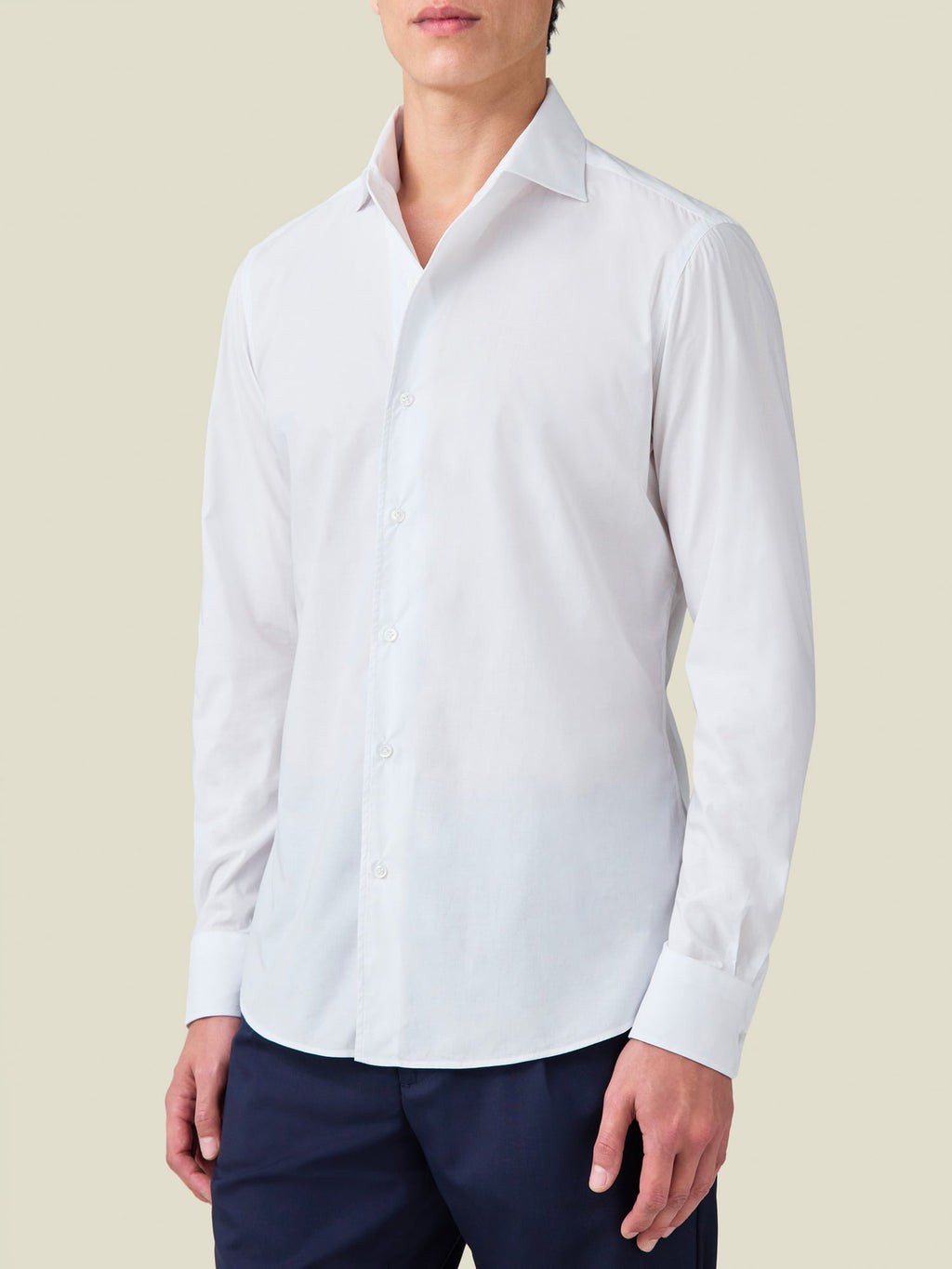 Front-side view of a model wearing the White Lightweight Poplin Cotton Shirt from Luca Faloni with navy trousers.