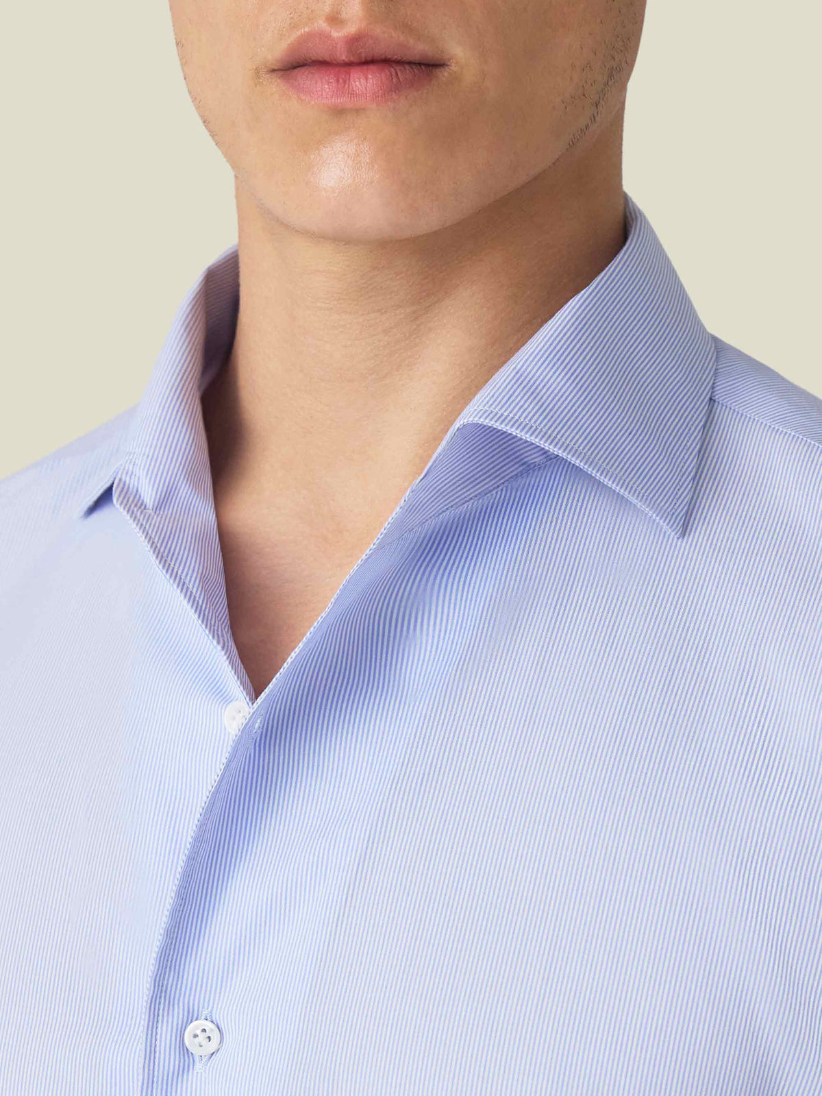 A close-up of the striped light blue Lightweight Poplin Shirt, highlighting the signature one-piece collar and fabric.