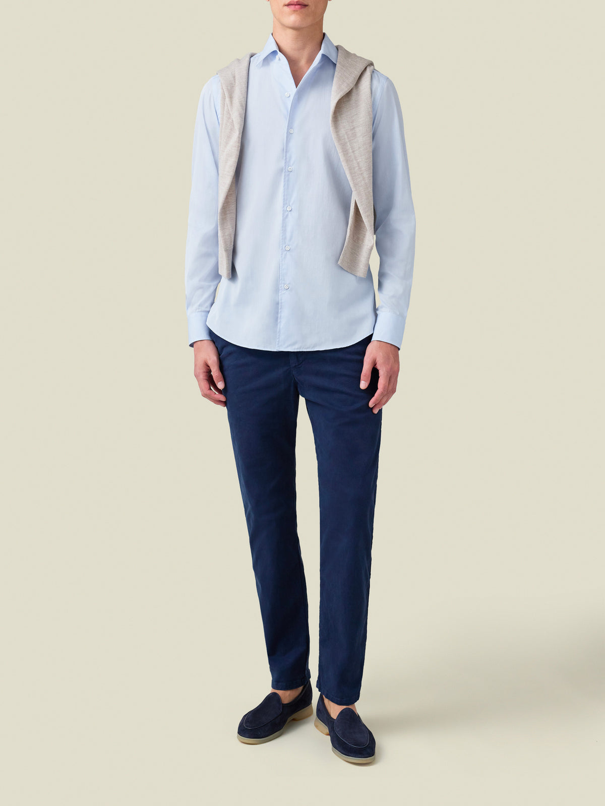 Model wears the Light Blue Poplin Cotton Shirt with navy trousers, navy loafers, and a sweater over the shoulders.