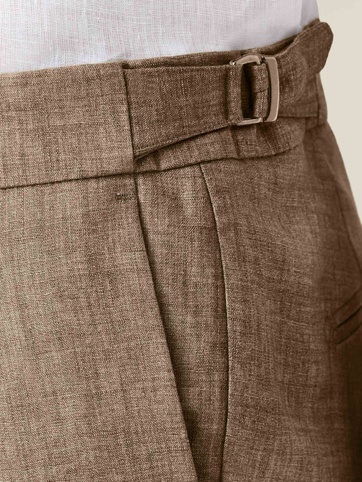 Detailed close-up of the Hazelnut Brown Linen Suit trousers, highlighting the side adjuster, pleated front, and linen fabric.