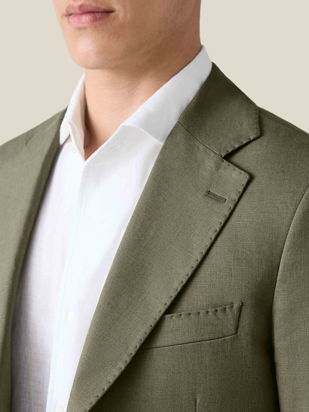 A close-up of the Olive Green Linen Suit jacket, detailing the notch lapel, fine stitching, and textured Italian linen.