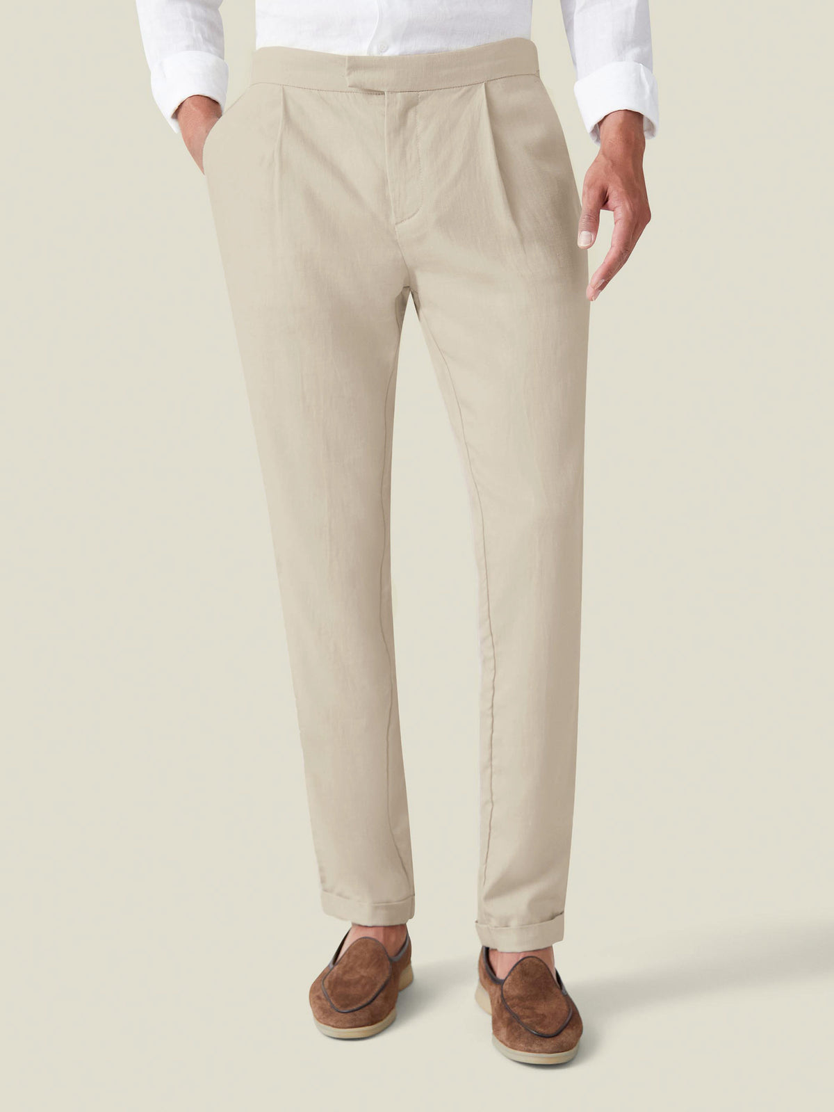 A man models the Luca Faloni Sand Elegant Linen Trousers, paired with a white shirt and brown suede loafers.