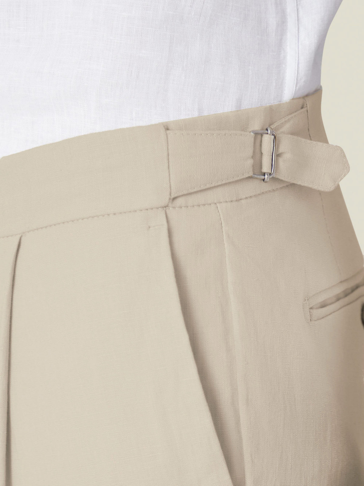 A close-up of the side adjuster detail on the Luca Faloni Sand Linen Trousers, worn with a white linen shirt.