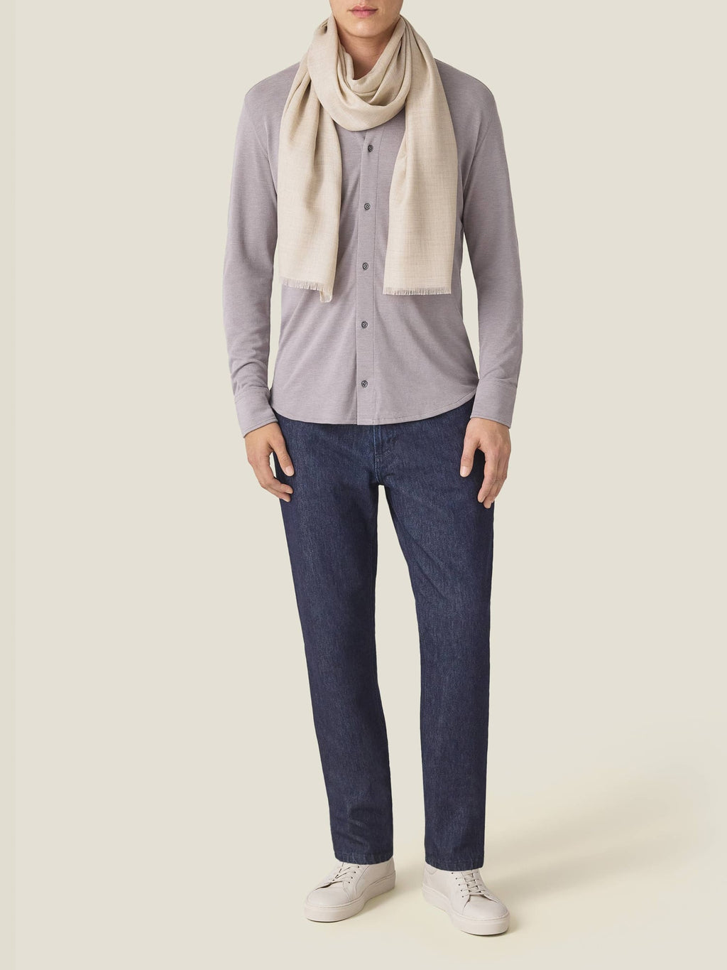 Front view of a man wearing the Nocciola Brown Silk-Cotton Piqué Shirt with a cream scarf, jeans and white sneakers.