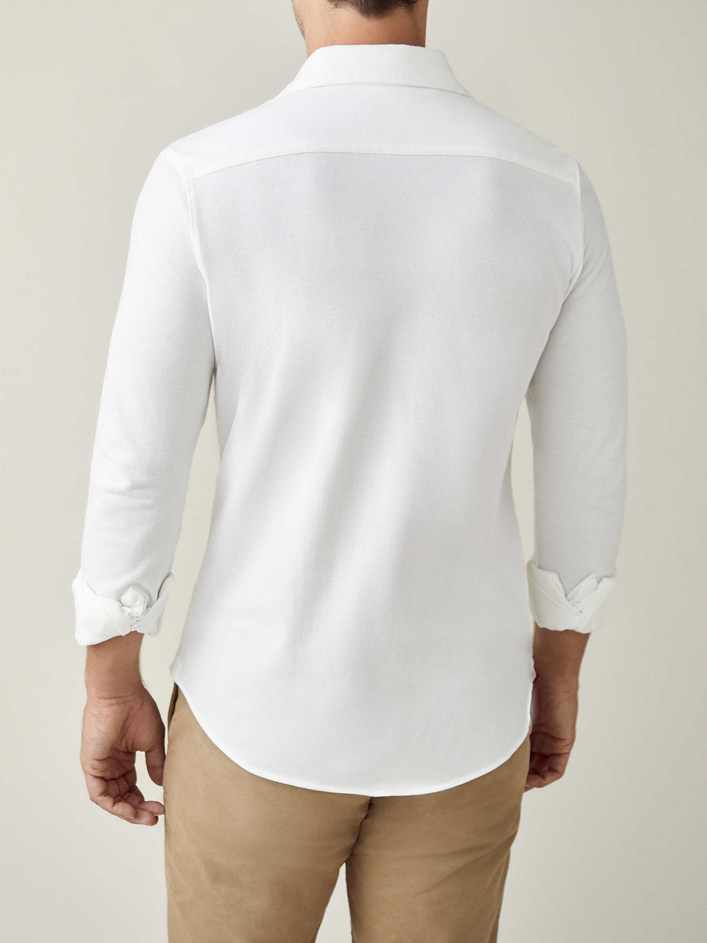 Back view of a model wearing the Luca Faloni white Silk-Cotton Piqué Shirt with the sleeves rolled up.